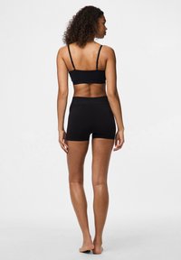 Reggiseno sportivo nero e pantaloni aderenti, entrambi realizzati in tessuto liscio. Spalline regolabili sul reggiseno, cintura senza cuciture sui pantaloni.