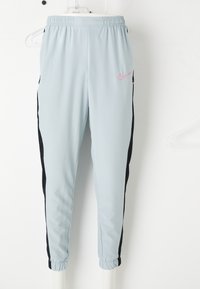 Pantaloni de sport blue deschis, cu panouri negre pe laterale, talie elastică și logo roz Nike pe coapsa superioară. Mansete elastice la glezne.