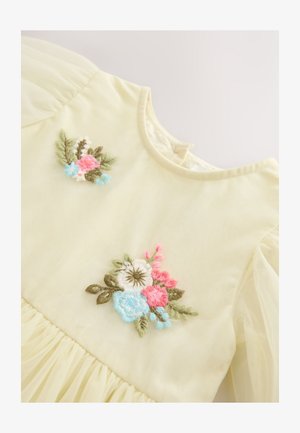 Rochie galben pal cu mâneci bufante, decorată cu broderii florale roz, albastre și albe. Tivul adunat adaugă textură designului.