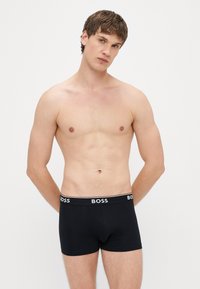 Μαύρα ανδρικά μποξεράκια με απαλή υφή, διακοσμημένα με λευκό λογότυπο "BOSS" στη ελαστική μέση. Απλός σχεδιασμός, εφαρμοστή γραμμή.