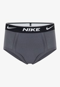 Šedé športové spodné prádlo s čiernym pásom, na ktorom je logo Nike v bielej farbe. Hladká tkanina, priliehavý strih a kontrastné švy.