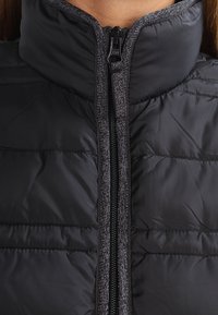 Czarna kurtka puchowa z wysokim kołnierzem i pełnym zamkiem, z pikowaną teksturą i szarymi akcentami wzdłuż zamka i szwów.