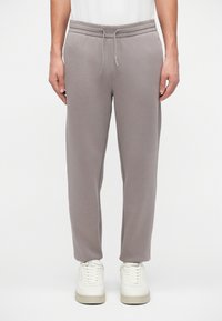 Pantaloni de trening gri, confecționați dintr-un material moale, cu talie elastică și șnur ajustabil, având o croială lejeră și picioare conice.