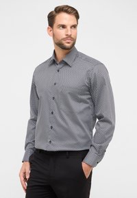 Zwart-wit gestreepte blouse met lange mouwen en een button-down kraag, voorzien van een geometrisch ontwerp en een gladde textuur.