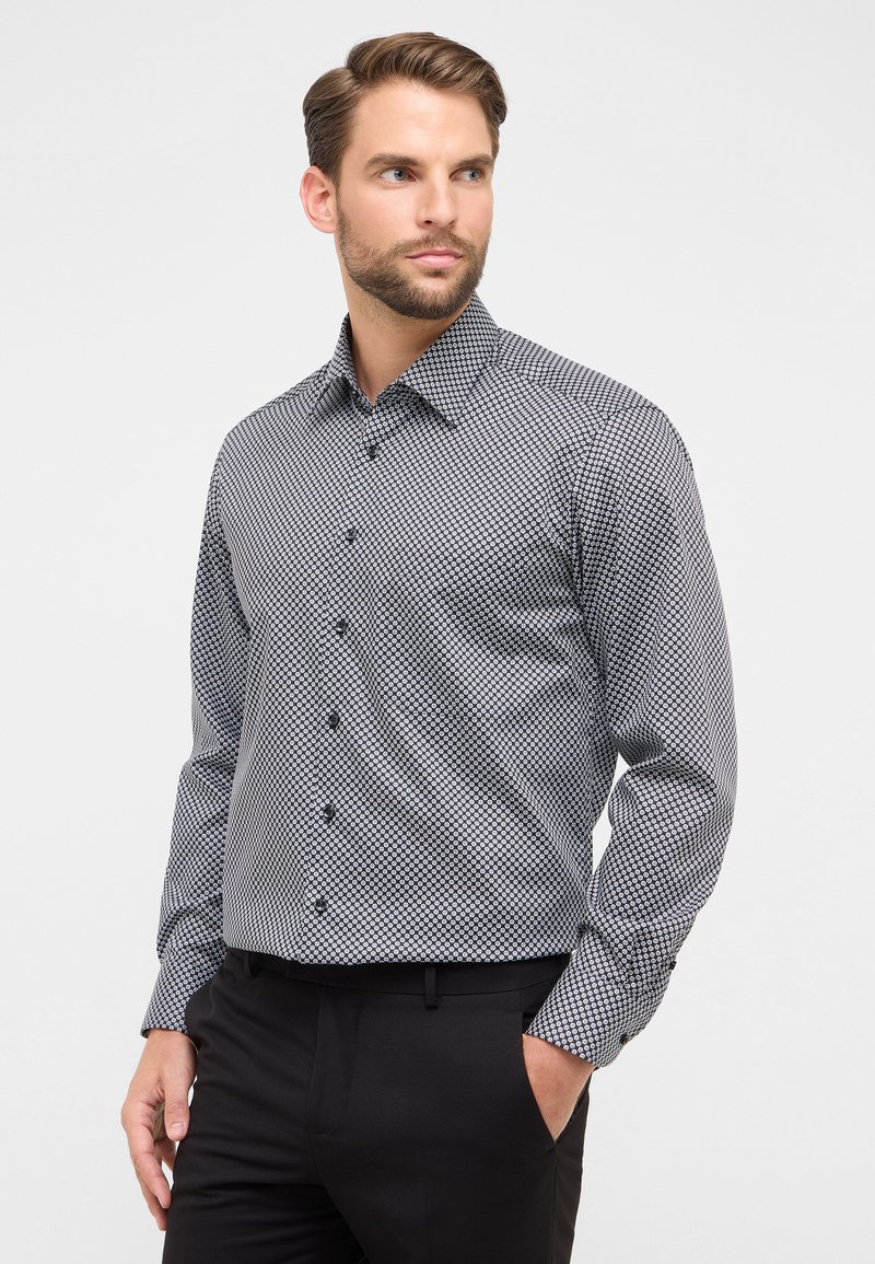 Zwart-wit gestreepte blouse met lange mouwen en een button-down kraag, voorzien van een geometrisch ontwerp en een gladde textuur.