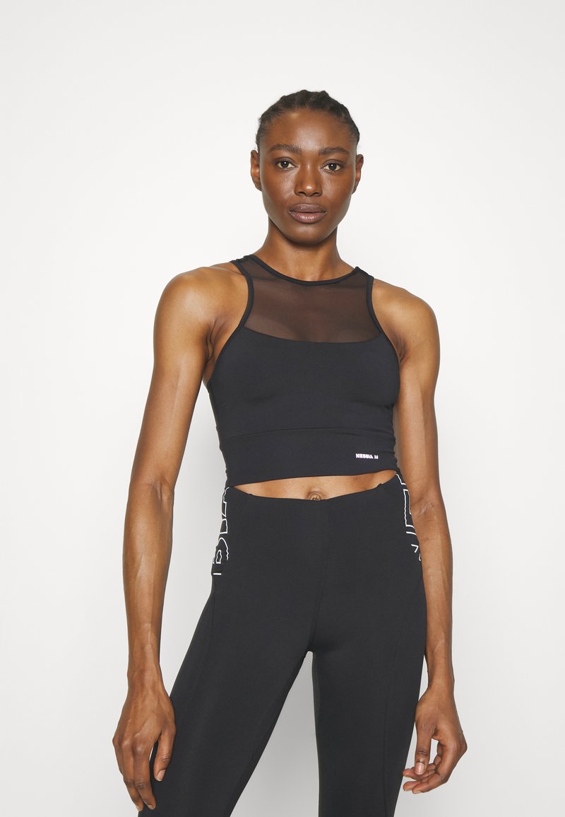 Top deportivo negro corto con un panel de malla, que presenta un escote redondo y tirantes anchos. Combinado con leggings negros de cintura alta con acentos laterales.