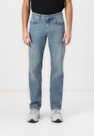 Light blue denim jeans with a straight leg fit, five pockets, and a button-fly closure. Worn with gray athletic shoes.
