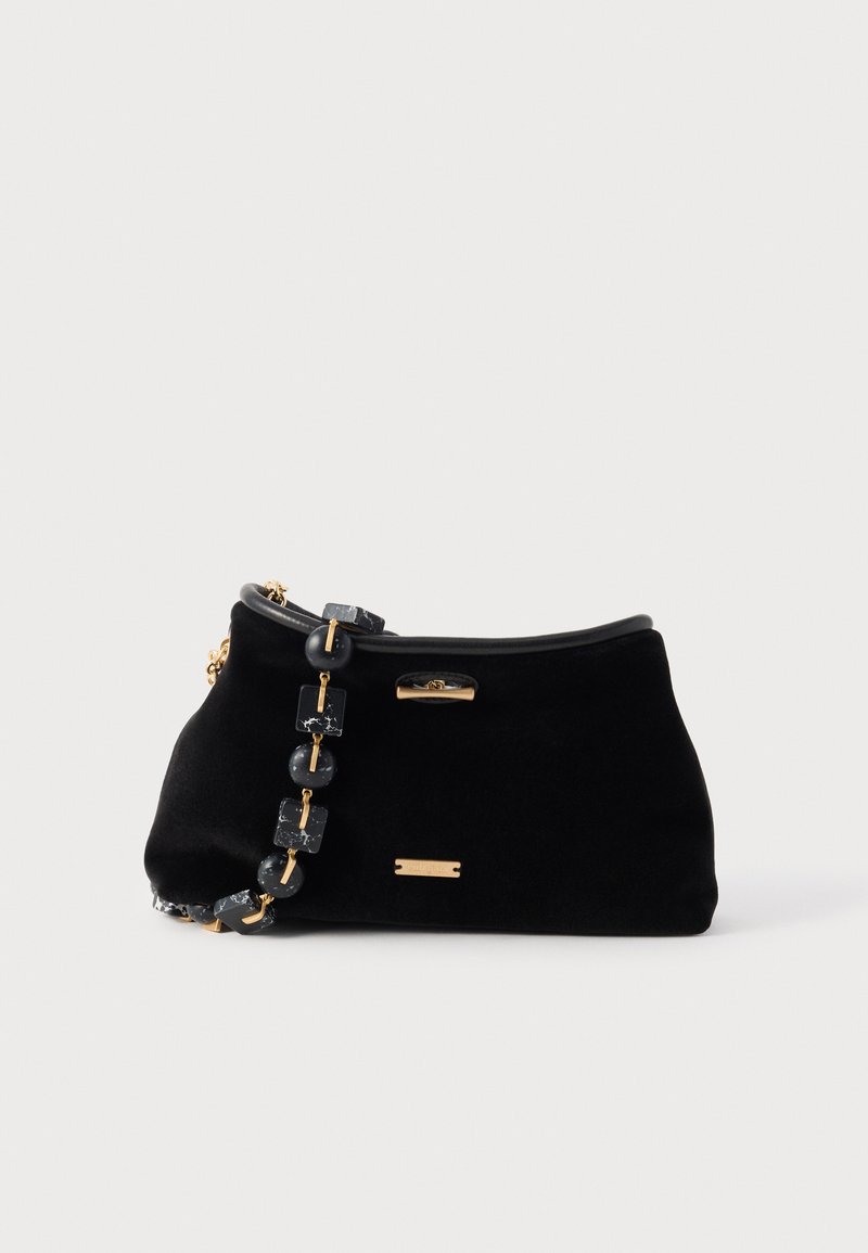 Mala de veludo preta com forma curva, ferragens douradas e uma alça decorativa em corrente com contas pretas e detalhes rectangulares.
