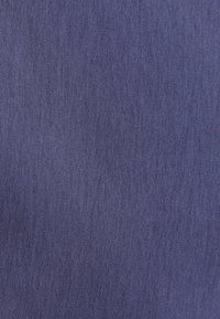 Gros plan sur la texture d'un tissu tissé bleu foncé avec de petits fils visibles et de fines impressions à la surface.