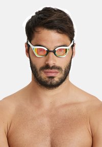 Svartvita simglasögon med tonade orangea och gula linser, med en snygg design och texturerad ram, bärs av en person utan tröja.