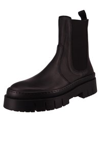 Botas Chelsea de cuero negro con paneles laterales elásticos, suela gruesa y estriada, y costuras reforzadas a lo largo de los bordes.