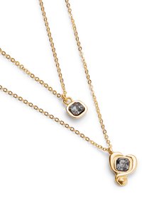 Collar en tono dorado con capas que presenta dos cadenas, una con una piedra preciosa gris cuadrada y la otra con un colgante redondeado, ambas adornadas.