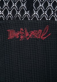 Tissu noir avec un motif texturé, comportant une section supérieure en dentelle. Inclut le logo "Desigual" brodé en rouge.