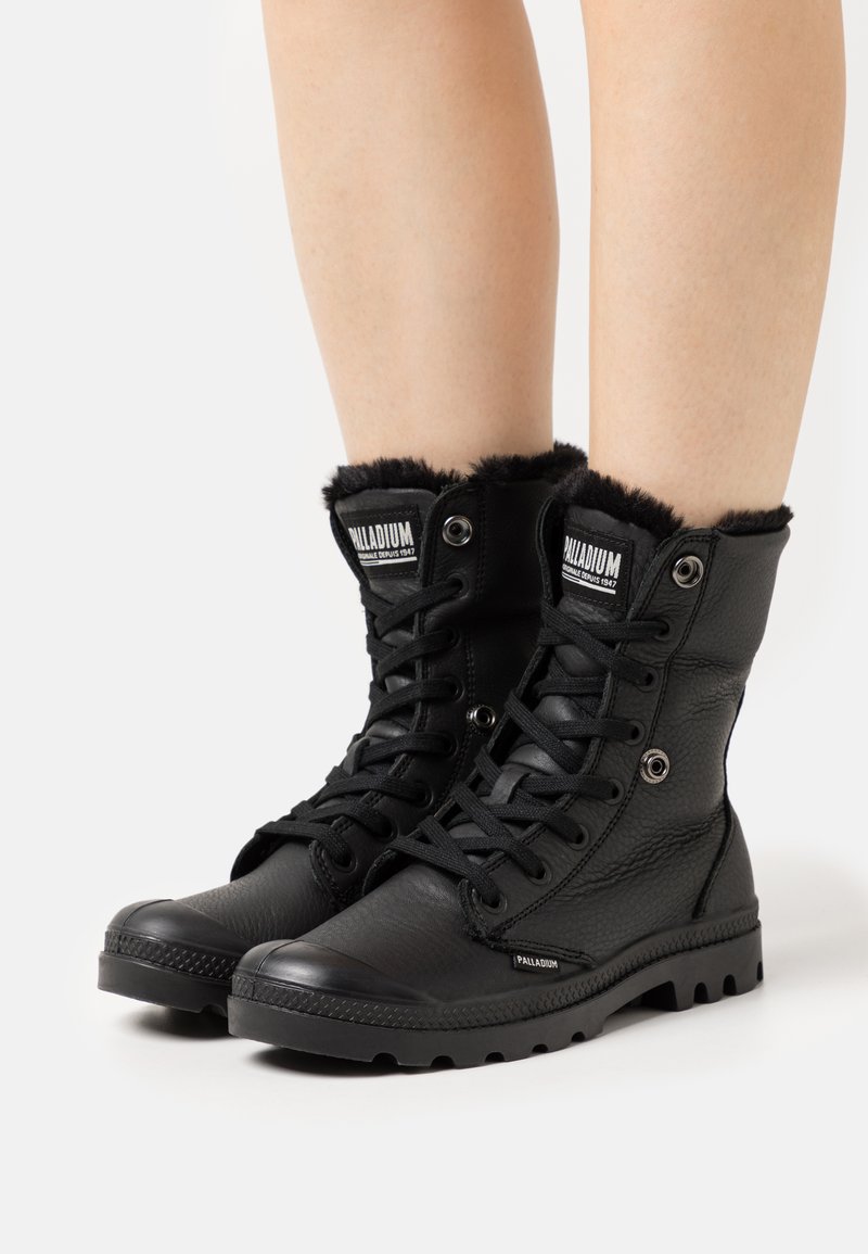Bottines noires en cuir texturé, dotées d'une doublure en fausse fourrure, de œillets en métal et d'une semelle en caoutchouc robuste avec un motif de traction.