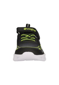 Baskets de sport noires avec une tige texturée, des accents vert néon, un design à lacets et une bande Velcro. Présente une semelle blanche pour un contraste supplémentaire.