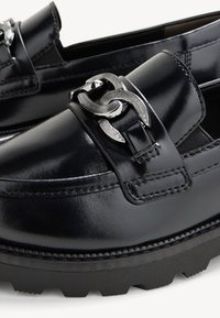 Black leather loafers with a silver chain accent, featuring a smooth texture, rounded toe, and rugged rubber outsole for grip.