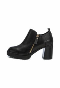Botas de tobillo de cuero negro con tacón grueso, detalle de cremallera lateral, suela texturizada y acabado suave. Cuenta con una lengüeta en la parte posterior.
