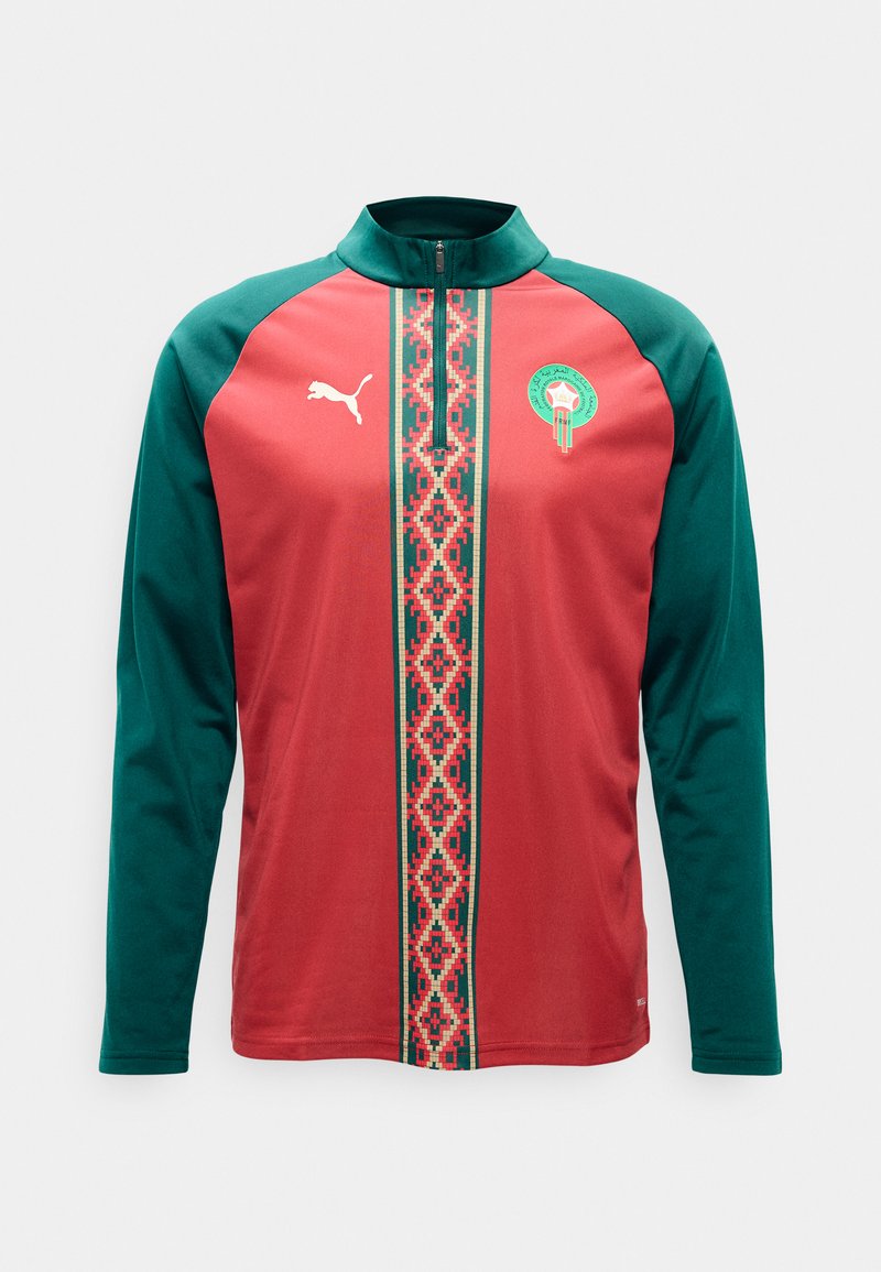 Langermet sportstopp med grønne ermer, rød kropp, sentralt geometrisk mønster, halvglidelåsåpning ved kragen, Puma-logo og Marokkos fotballemblem på brystet.
