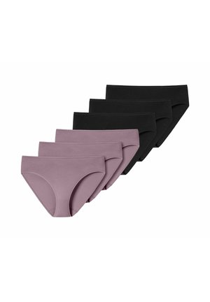 Femme aux cheveux bouclés foncés portant un soutien-gorge et une culotte mauve assortis, posant avec la main sur le bras, regardant vers sa gauche sur fond blanc.
