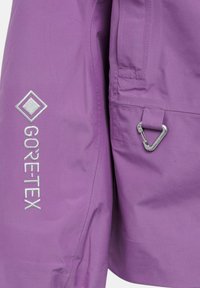 Jachetă purple din GORE-TEX, cu broderie logo argintie, textură netedă și un cârlig pe lateral pentru atașare.