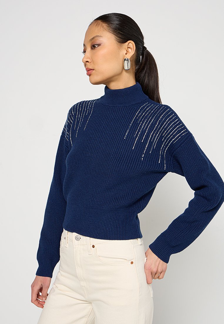 Maglione a collo alto in maglia blu navy con motivo testurizzato e dettagli decorativi sulle spalle. Silhouette aderente e maniche lunghe.