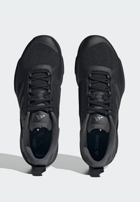 Zapatillas de entrenamiento negras con parte superior de malla, superposiciones texturizadas y cordones planos. Cuentan con un collar acolchado y suela de goma para mayor agarre.