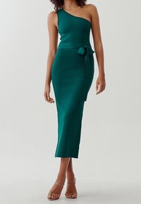Robe ajustée bleu sarcelle à une épaule, de longueur mi-cuisse, avec une taille accentuée par un noeud. Fabriquée dans un tissu lisse et texturé. Silhouette élégante.