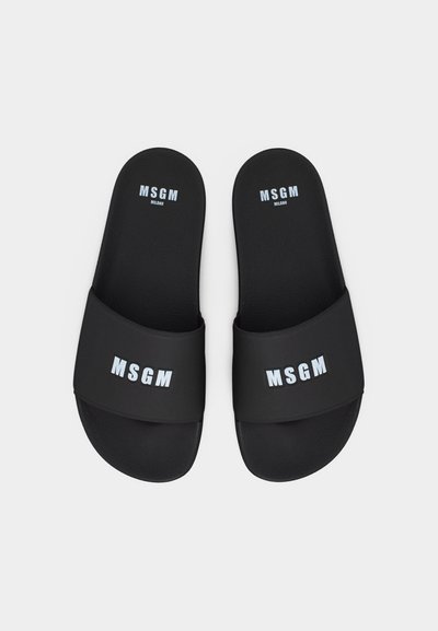 Paire de sandales à enfiler noires avec le logo blanc MSGM Milan sur les brides et les semelles, présentées sur un fond clair uni.
