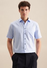 Camicia a maniche corte azzurro chiaro con colletto button-down, bottoni neri e taschino sul petto. Tessuto morbido e vestibilità aderente.