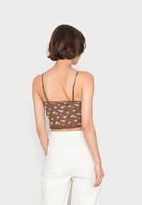 Top curto castanho com padrão floral branco, alças finas ajustáveis e renda na bainha. O tecido tem uma textura suave.