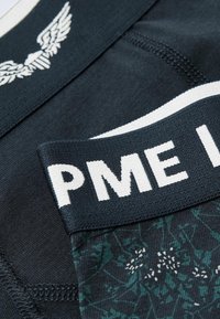 Boxers pour hommes en tissu bleu marine foncé avec un motif floral aux accents verts et blancs, dotés d'une taille élastique blanche avec "PME Legend".