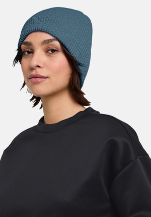 Blue knit beanie with a textured pattern, closely fitted to the head, paired with a plain black sweatshirt featuring a crew neck.