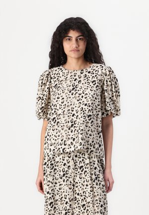 Leopard print blouse with short puff sleeves, cream background, and textured fabric. Hem falls slightly below the waist for a relaxed fit.
