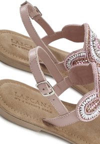 Sandalo rosa con soletta in suede, dettaglio di perline in un motivo a spirale e cinturino alla caviglia regolabile con fibbia in argento.