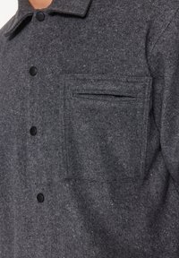 Šedá košile-jacket ze směsi vlny s knoflíkovou přední částí, černými knoflíky a náprsní kapsou s horizontálním otvorem.