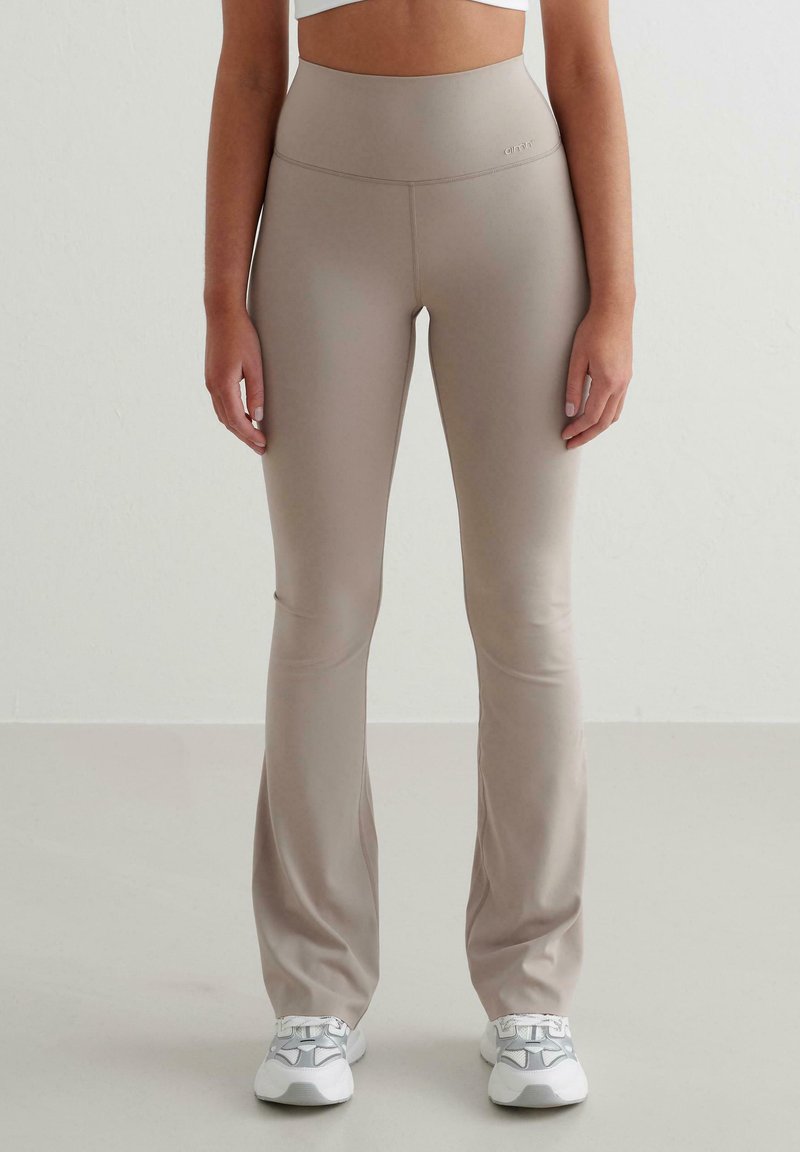 Beige utsvängda leggings gjorda av stretchigt material med hög midja. Har en jämn yta och diskret logotyp vid midjan.