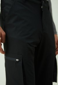 Black cargo pants with a smooth texture, featuring a zippered side pocket and a fitted design, made from lightweight, durable material.