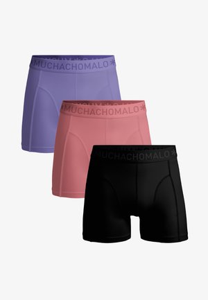 Tri muška bokserice u ljubičastoj, ružičastoj i crnoj boji s pojasevima s natpisom "MUCHACHOMALO" složene jednu na drugu na bijeloj pozadini.