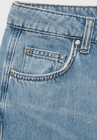 Helle blaue Denim-Jeans mit hohem Taillenbund, sichtbaren Nähten, einer einzelnen Vordertasche und metallischen Nietenakzenten. Glatte Textur.