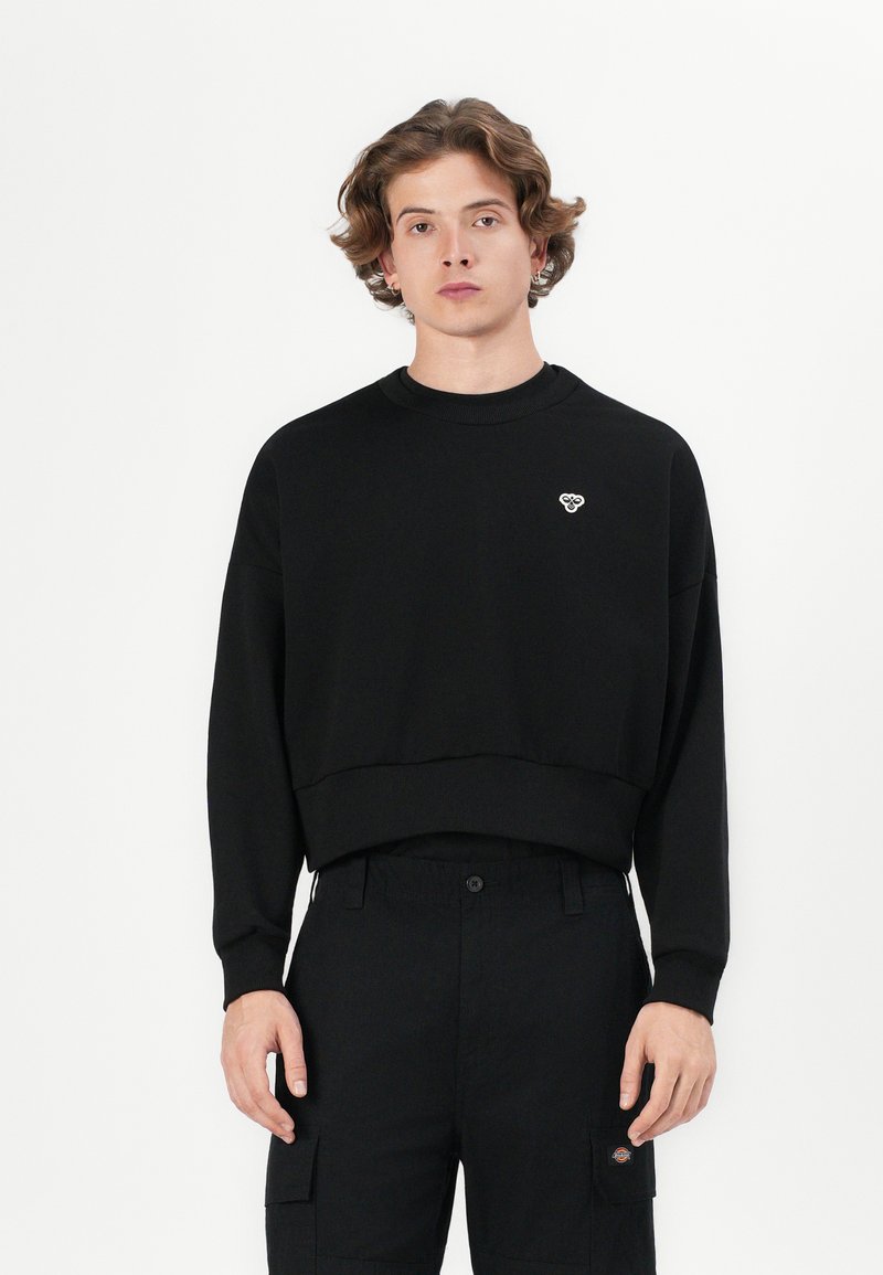 Black cropped sweatshirt made of soft fabric, featuring a round neck and a small embroidered logo on the left chest. Simple design.