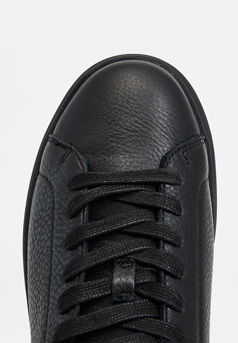 Schwarze Leder-Sneaker mit strukturiertem Finish, runder Zehenpartie, flachen Schnürsenkeln und einem gepolsterten Kragen für zusätzlichen Komfort. Glatte Sohle mit minimalem Akzent.