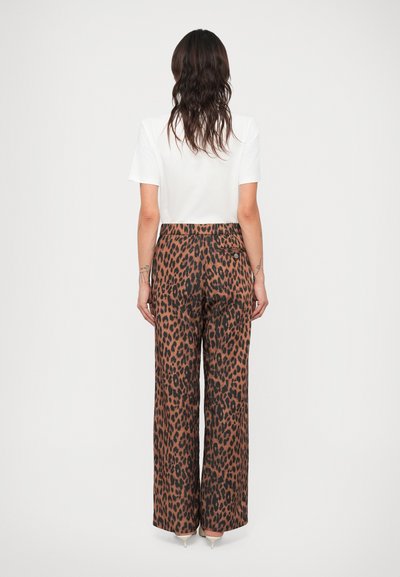 Leopardimustriga laiad püksid pruuni ja musta värviga, millel on kõrge talje, pehme kangas ja taga tasku detail, koos valge T-särgiga.