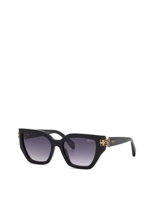 Lunettes de soleil noires oversize en forme d’œil de chat avec verres foncés dégradés et ornements floraux dorés sur les branches.
