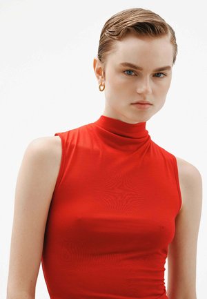 Top sin mangas rojo con un escote alto, hecho de una tela suave y elástica, que presenta un diseño ajustado y costuras mínimas para un aspecto elegante.