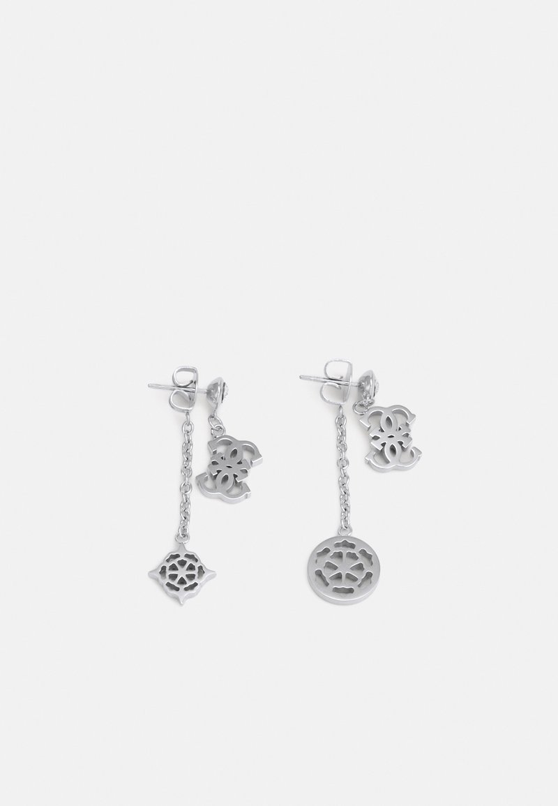Boucles d'oreilles pendantes en argent dépareillées avec des dessins découpés complexes, l'une avec un cercle et l'autre avec une forme de diamant aux extrémités des chaînes.