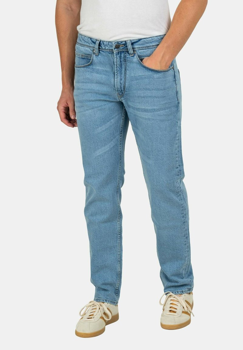 Vaqueros de mezclilla azul claro con un ajuste regular, diseño de cinco bolsillos y una textura sutil. Combinados con zapatillas blancas y una camiseta sencilla.