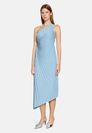 Asymetryczna sukienka na jedno ramię z jasnoniebieskiej tkaniny, z detalami drapowania i dopasowanym górnym partiem. Stylizowana z metalicznymi srebrnymi butami.