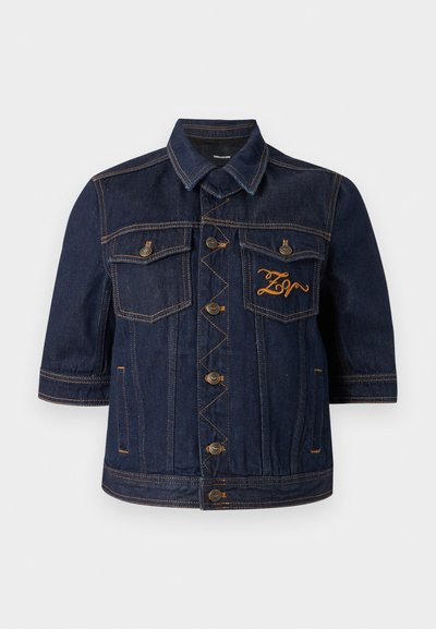 Σκούρο μπλε μπουφάν τζιν με κοντά μανίκια, δύο τσέπες στο στήθος, χρυσή κεντητική και χαλκούς κουμπιά. Διαθέτει ορατές λεπτομέρειες ραφής.