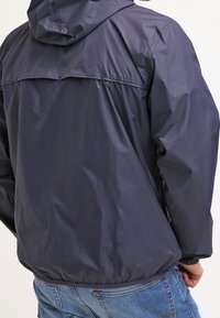 Marinblå lättviktsjacka med huva, slät yta, elastiska cuffs och en zippered bakventilation. Har en avslappnad passform och minimalistisk design.