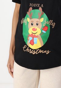 Black t-shirt featuring a cartoon reindeer with antlers, red nose, and gloves, holding a gift with "Have a holly jolly Christmas" text.